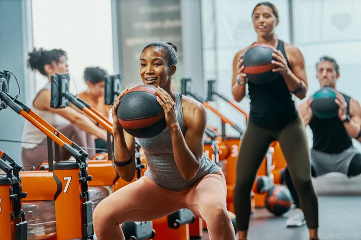 Members doing medicine ball squats on the studio floor